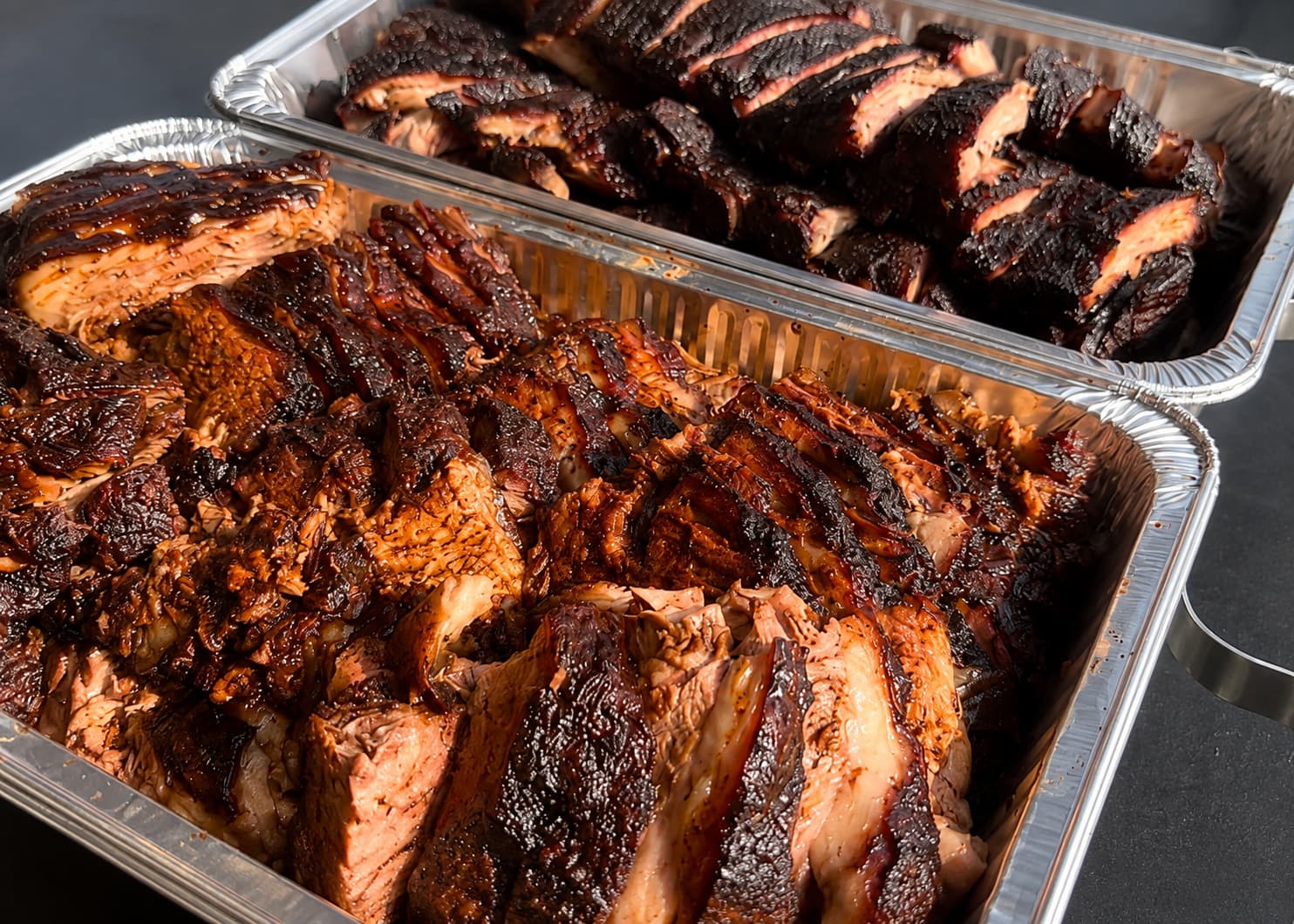 Foil catering trays of sliced smoked brisket