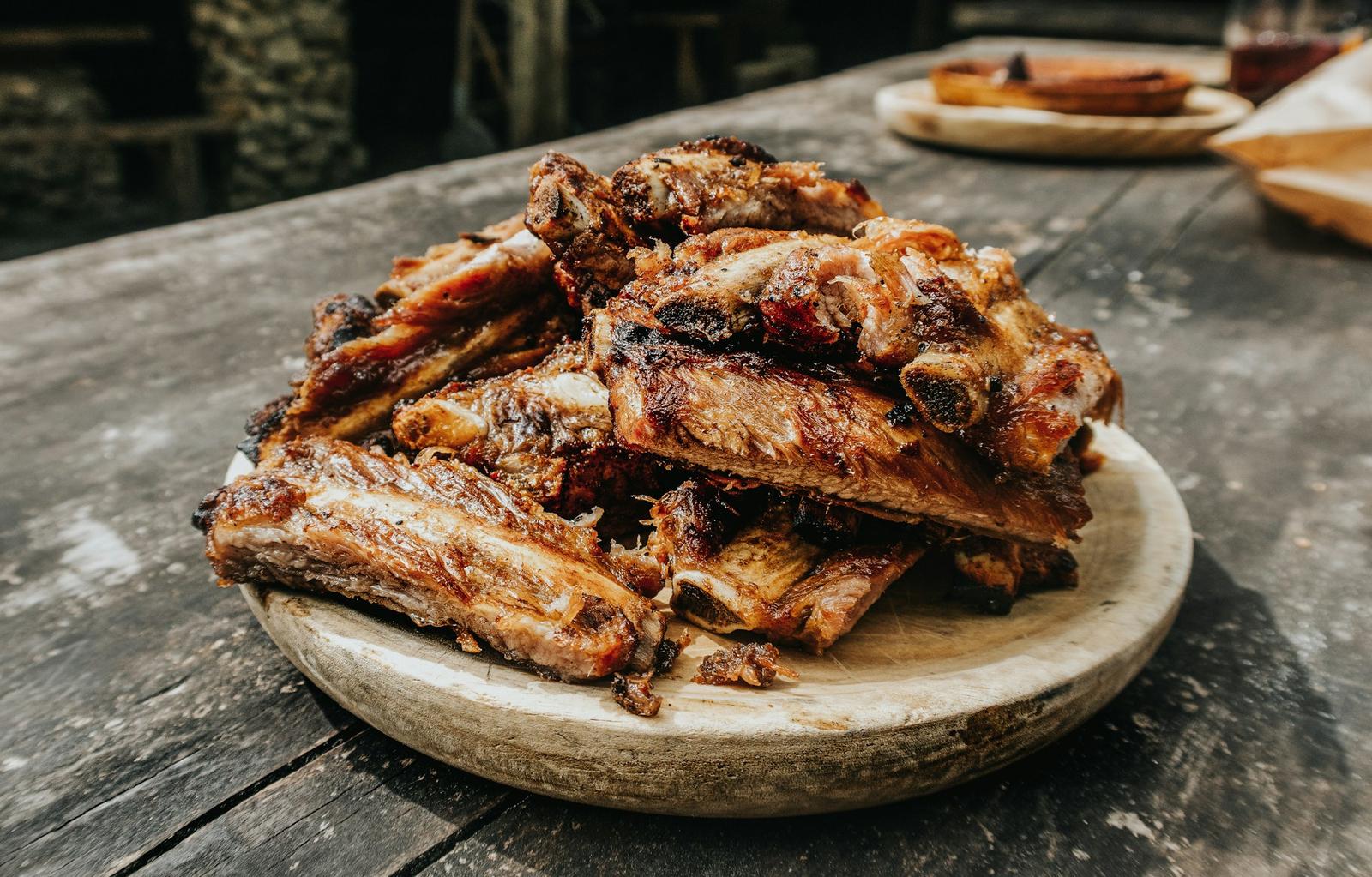 Rack of grilled pork ribs on brown wooden tray