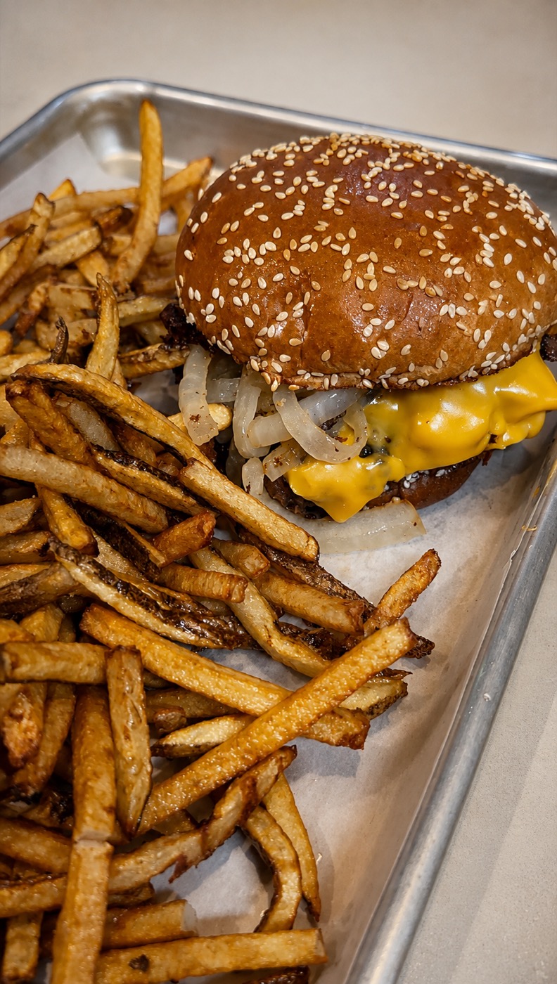 Smash burger on a sesame bun with griddled onions, American cheese, and hand-cut fries