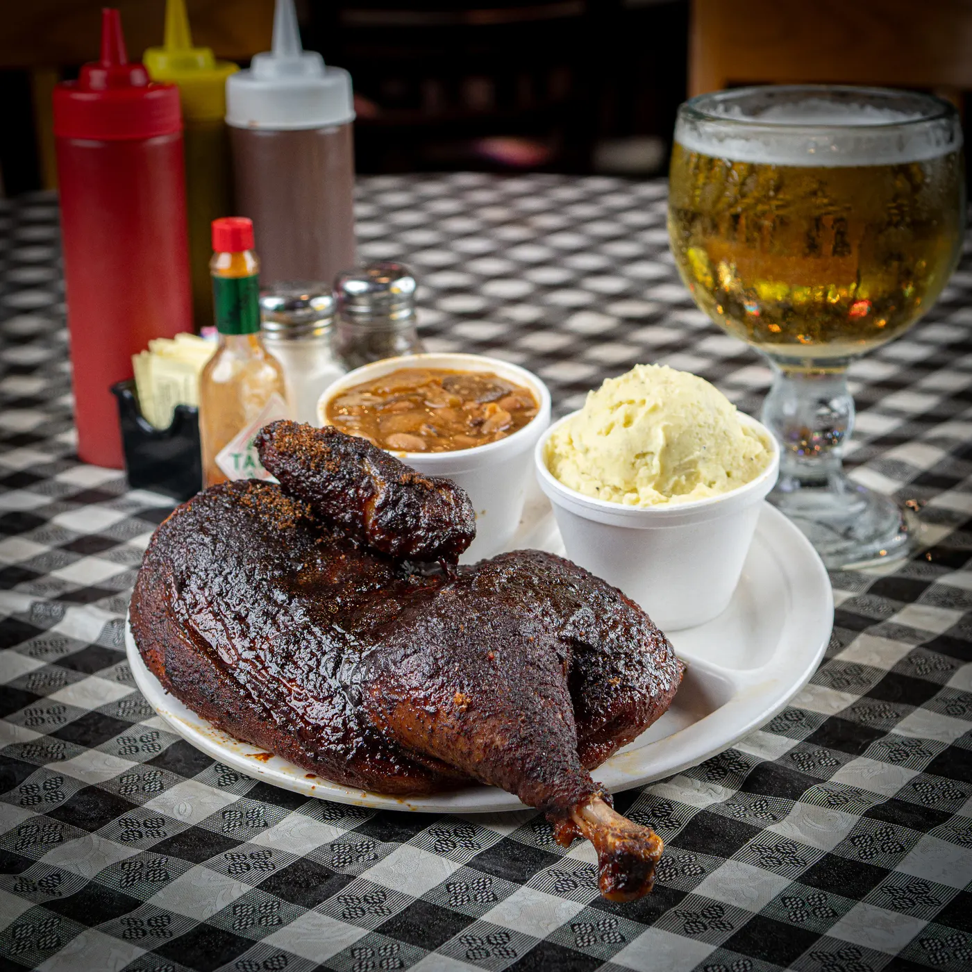 Half a smoked chicken on a plate with beans and potato salad